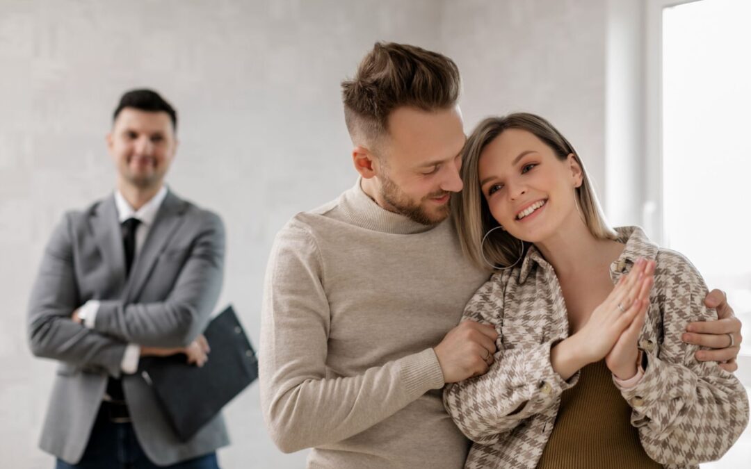 Smiling couple with real estate agent celebrating new home purchase indoors.